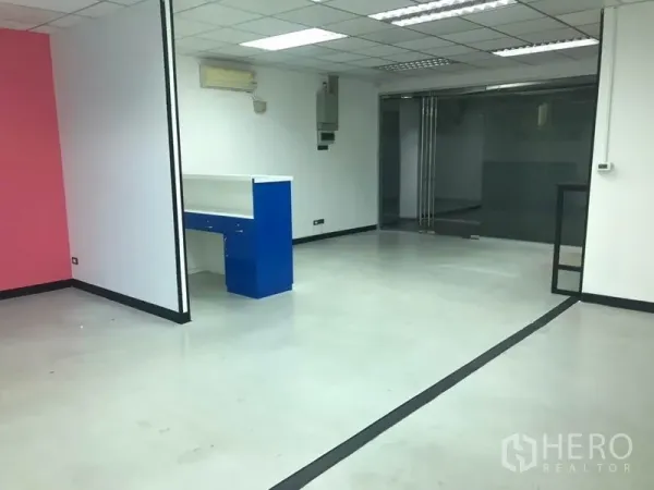Office Space for rent in Khlong Toei, Bangkok - Spacious office area with a blue reception counter, sliding glass door, and pink accent wall.