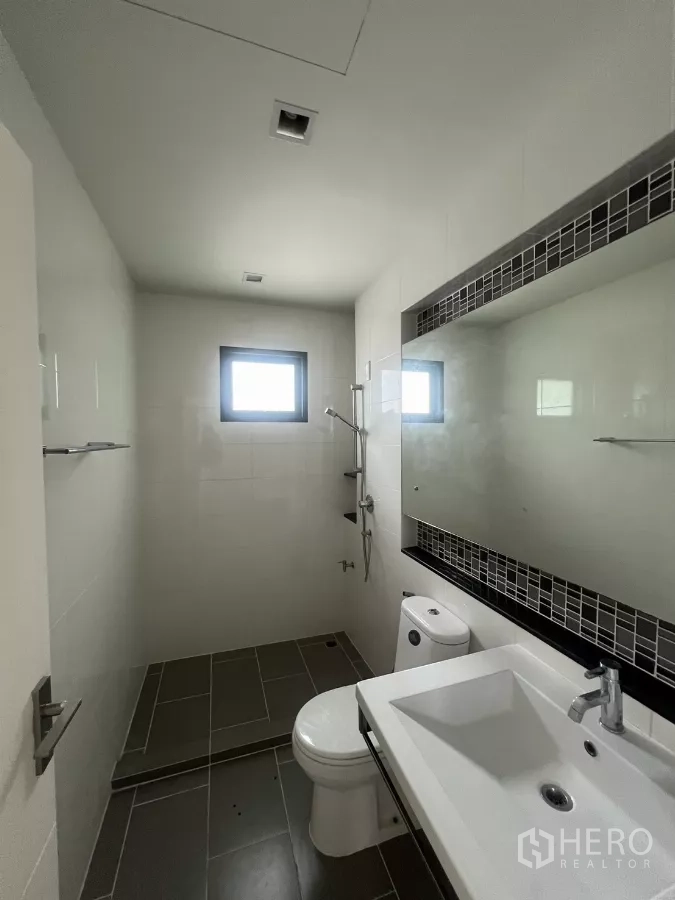 Detached House for sale in Bang Kapi, Bangkok - Bathroom with walk-in shower, vanity sink, and small window for ventilation.