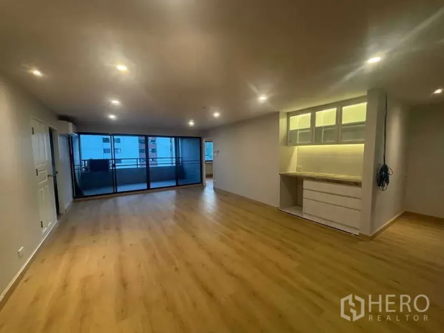 Condominium for sale - Wide living room with floor-to-ceiling glass opening to a covered balcony.