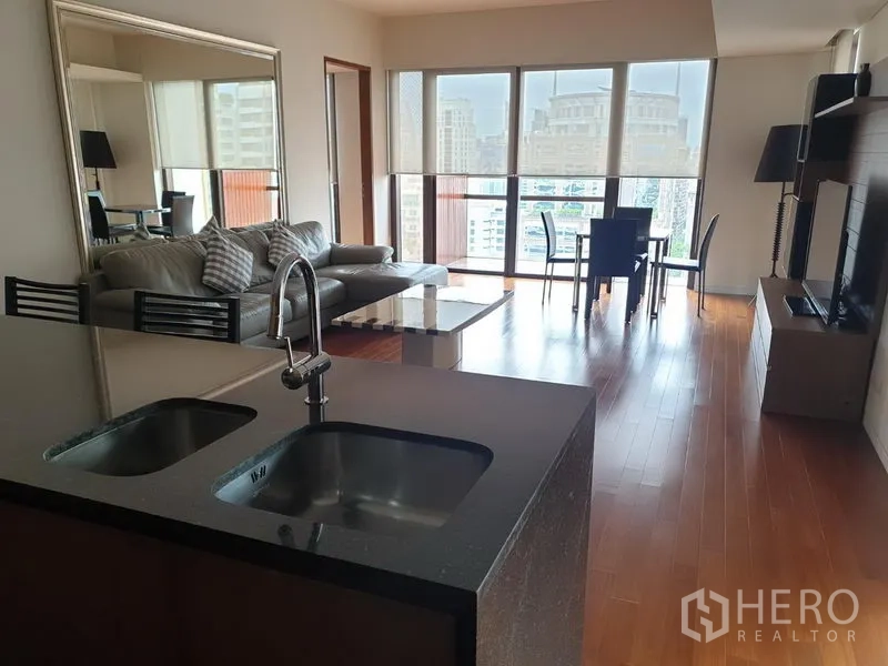 Condominium for rent in Pathum Wan, Bangkok - Open-plan living and dining area at Hansar condo with island kitchen, floor-to-ceiling windows and city views.