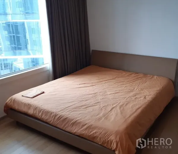 Condominium for sale in Khlong Toei, Bangkok - Cozy bedroom with large bed, big window and skyline outlook.