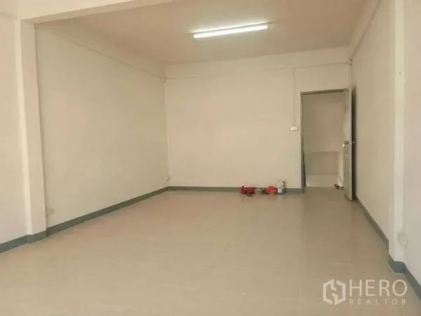 Shophouse for rent in Bang Na, Bangkok - Open-plan ground floor with tiled flooring, white walls and fluorescent lighting.