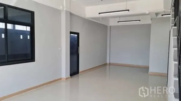Warehouse for rent in Bang Bua Thong, Nonthaburi - Ground-floor office room with tiled floor, large window, and glass entry door.
