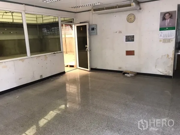 Warehouse for rent in Mueang Samut Prakan, Samut Prakan - Glass-partitioned office room inside the warehouse with tiled floor and fluorescent lighting.