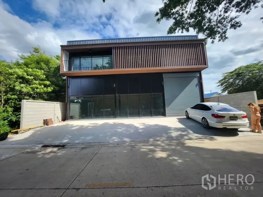 Warehouse for rent in Lam Luk Ka, Pathum Thani - Modern two-storey warehouse facade with roller shutter and wide parking forecourt.