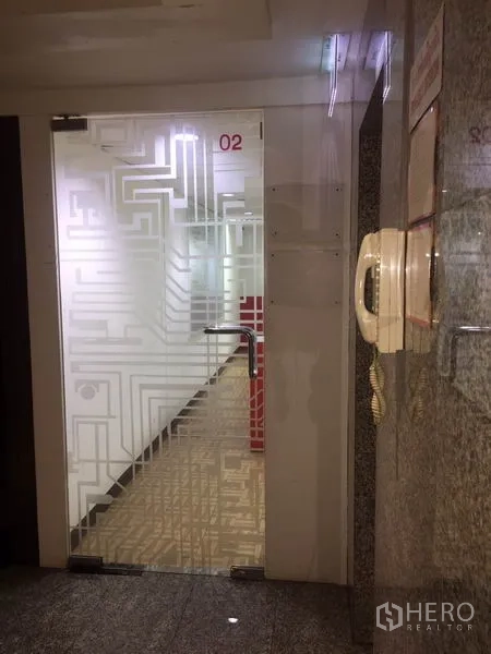 Office Space for rent in Watthana, Bangkok - Building corridor with frosted patterned glass door and intercom access.
