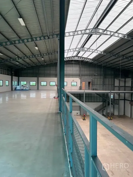 Warehouse for rent in Bang Phli, Samut Prakan - Spacious interior featuring a mezzanine walkway, steel beams, and skylight roof panels.