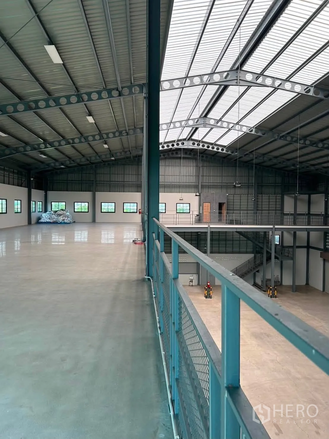 Warehouse for rent in Bang Phli, Samut Prakan - Spacious interior featuring a mezzanine walkway, steel beams, and skylight roof panels.