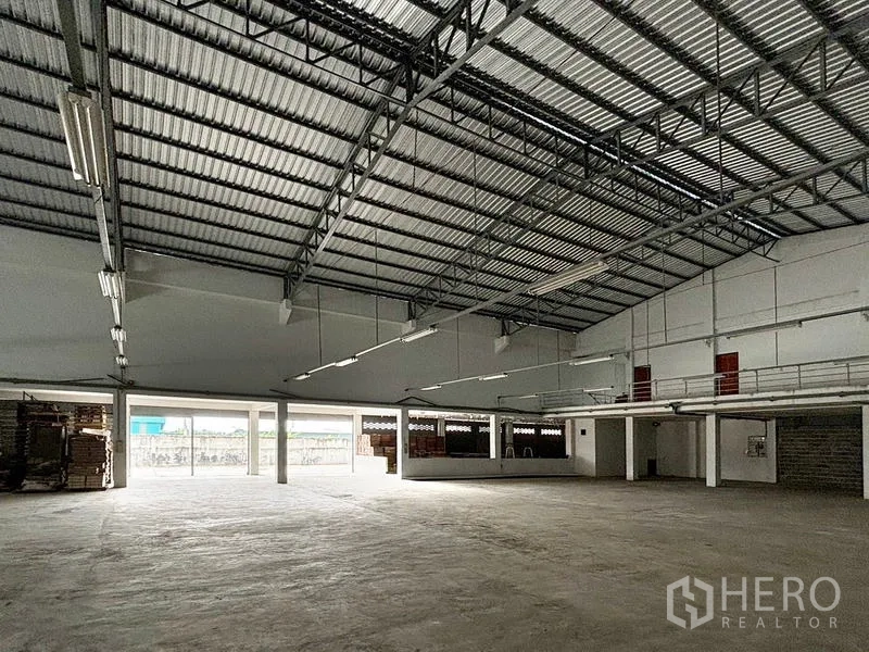 货栈 出租在Bang Khun Thian, Bangkok - 仓库地面配夹层办公区、红色安全门与宽阔装卸开口。