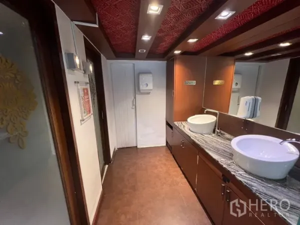 Retail Space for rent or sale in Khlong Toei, Bangkok - Restroom corridor with twin vessel sinks, granite counter and warm wood finishes inside the retail space.