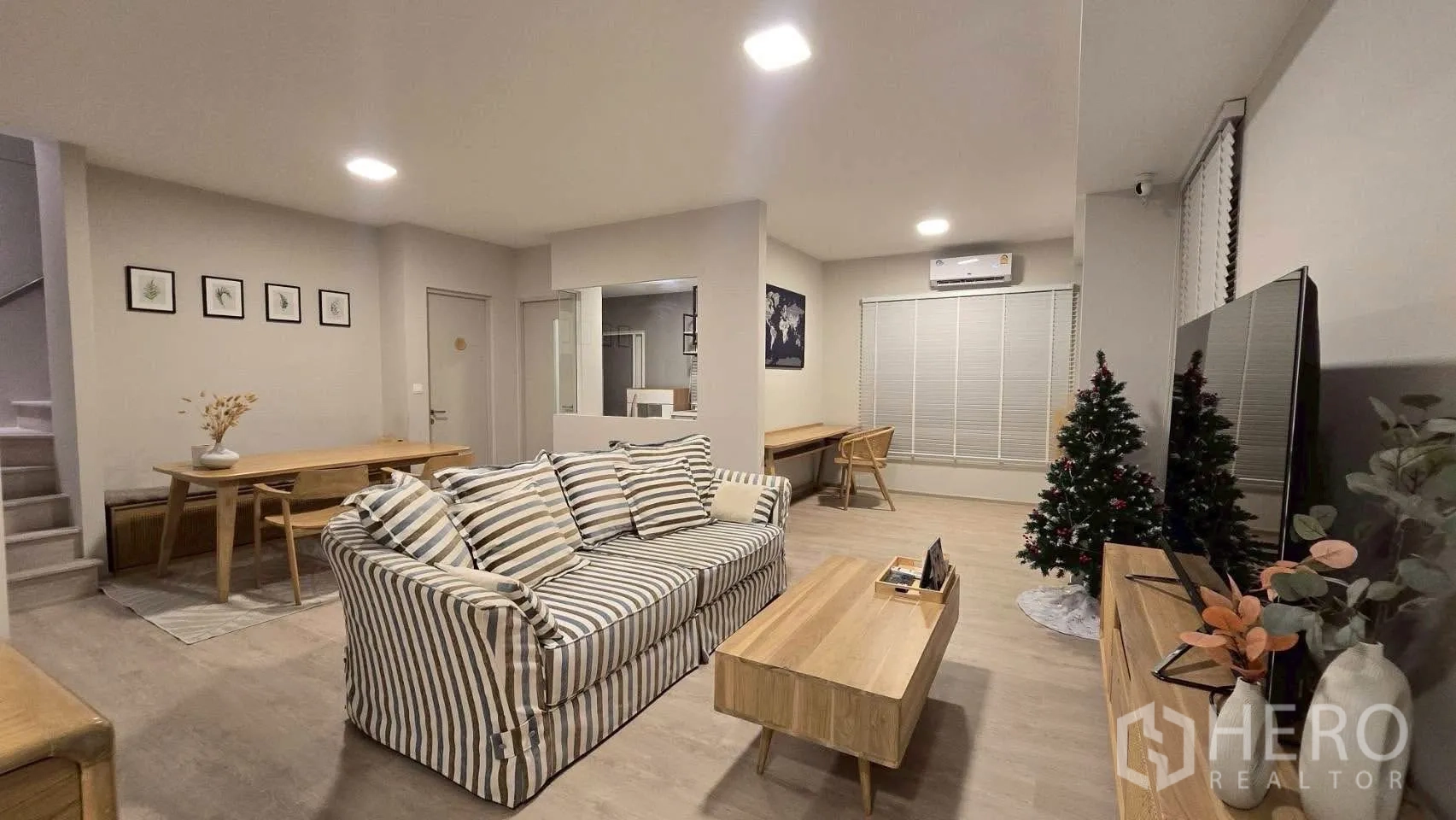 Semi-detached House for rent in Prawet, Bangkok - Open-plan living and dining area with striped sofa, TV and wooden furniture.