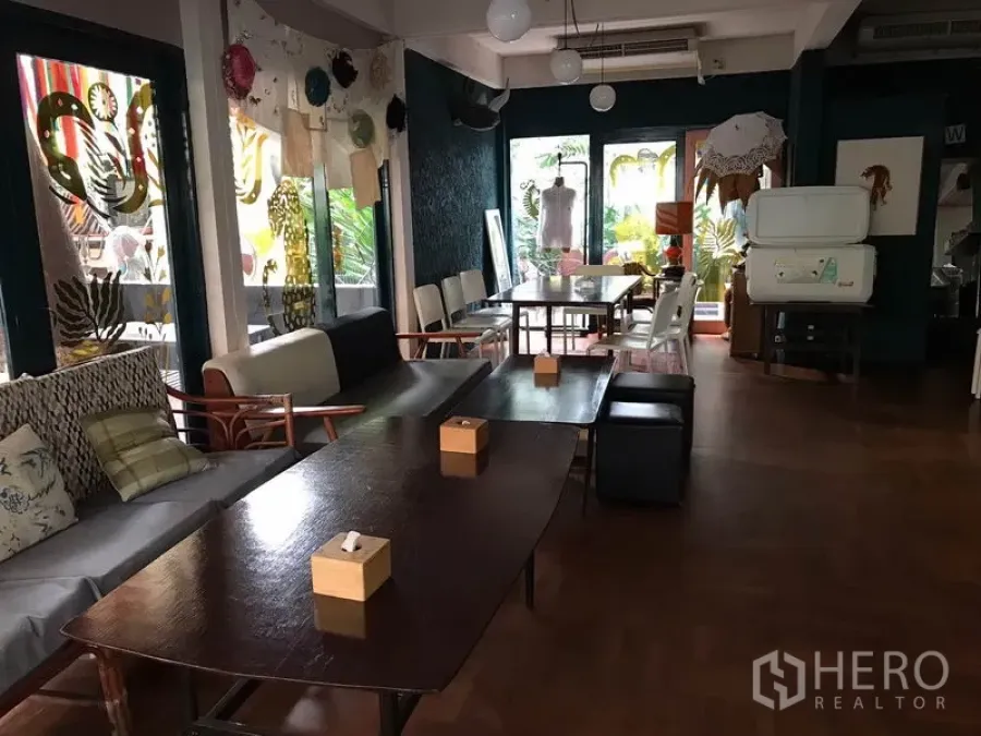 零售空间 出租在Watthana, Bangkok - 室内用餐区，木质餐桌、沙发座和吊灯。