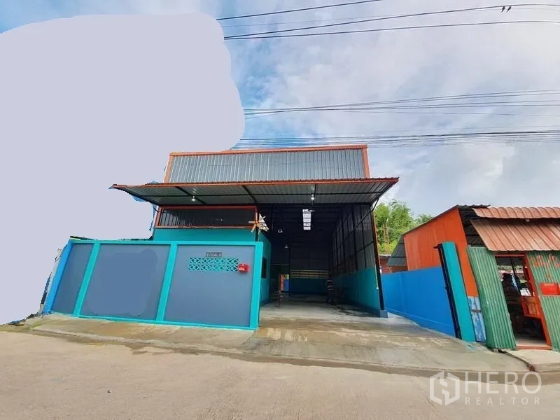 คลังสินค้า ให้เช่าในNonthaburi - มุมมองด้านหน้าโกดัง มีประตูรั้ว หลังคากันสาดโลหะ และทางเข้าคอนกรีต