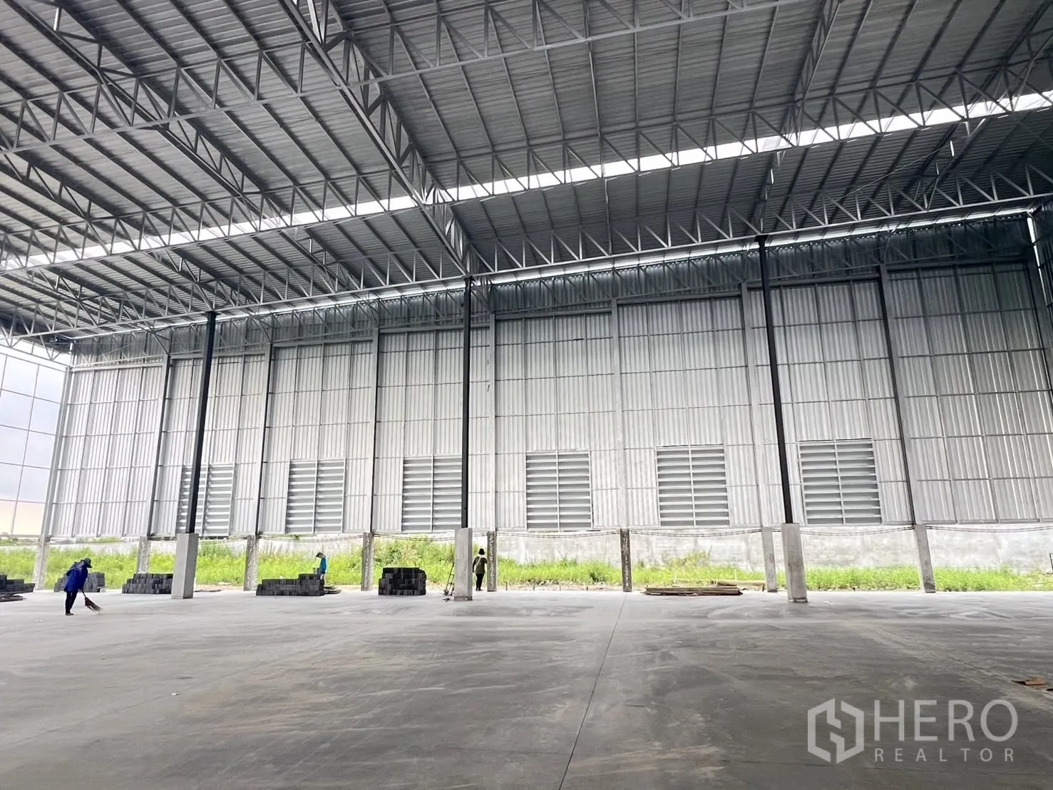 Factory for rent in Mueang Samut Prakan, Samut Prakan - Spacious factory interior with high steel truss roof, concrete floor, and wall ventilation louvers.