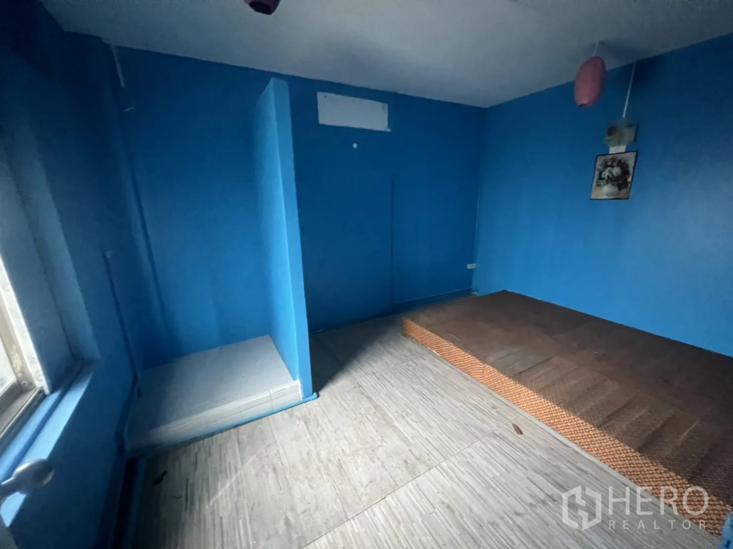Shophouse for rent in Watthana, Bangkok - Blue-painted room with a partitioned nook, window and raised platform.
