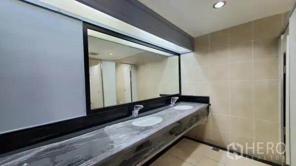 Office Space for rent in Watthana, Bangkok - Modern restroom featuring a long black counter with twin basins and a large wall mirror.