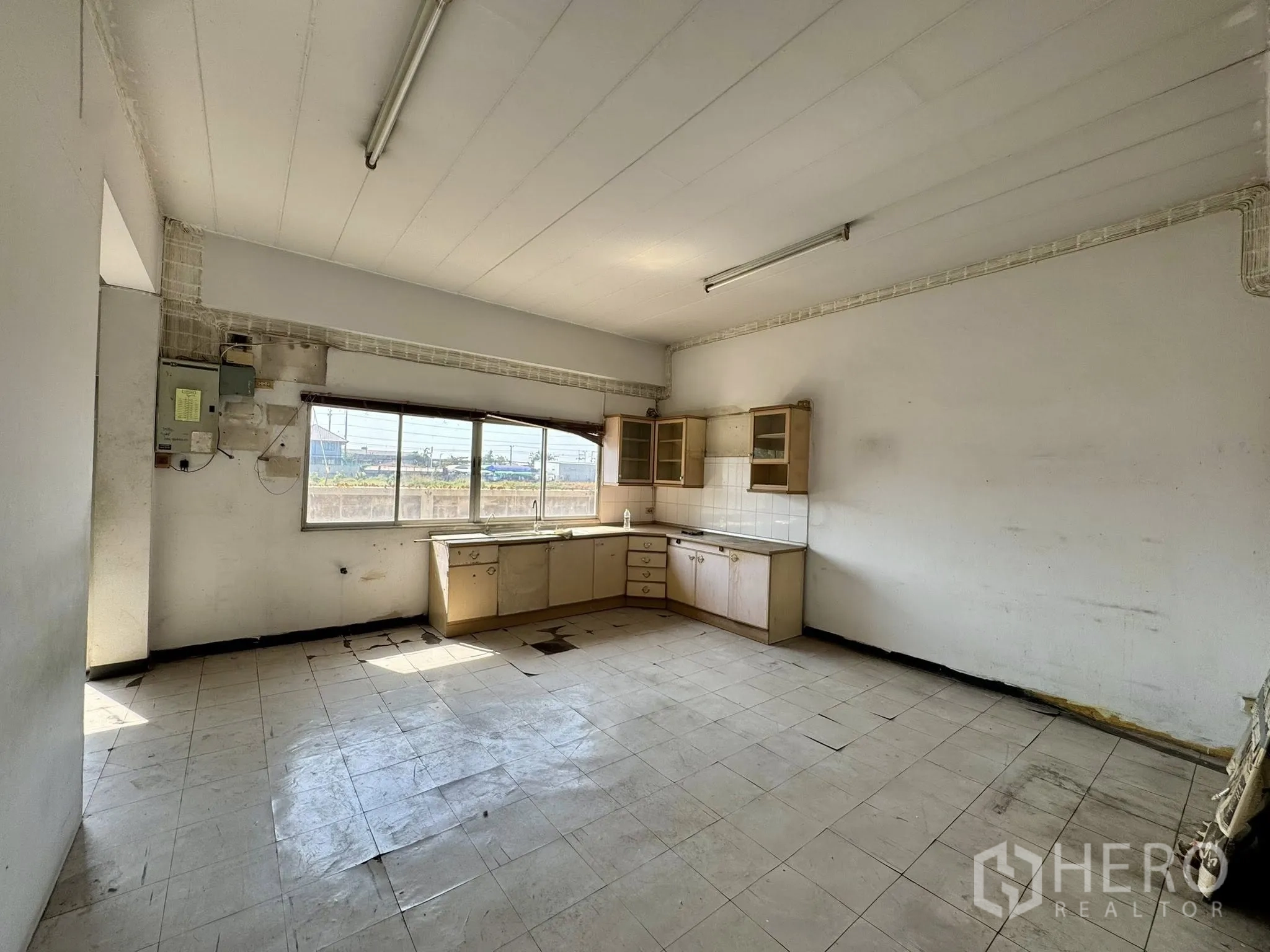 Warehouse for rent in Mueang Samut Sakhon, Samut Sakhon - Kitchenette space with built-in cabinets and a large window, ready for refurbishment.