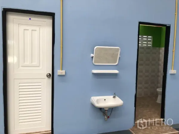 Warehouse for rent or sale in Sai Noi, Nonthaburi - Restroom block with blue wall, white door, wall-mounted sink, mirror and tiled bathroom.