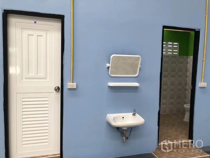 Warehouse for rent or sale in Sai Noi, Nonthaburi - Restroom block with blue wall, white door, wall-mounted sink, mirror and tiled bathroom.