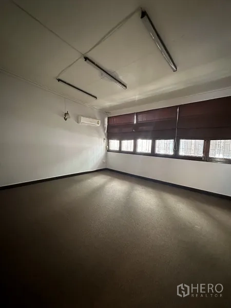 Detached House for rent in Watthana, Bangkok - Large bedroom with carpet-style flooring, split air conditioner and shuttered windows.