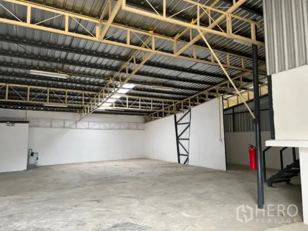 货栈 出租在Suan Luang, Bangkok - 宽敞仓库地面，照明充足，钢梁结构与楼梯旁灭火器