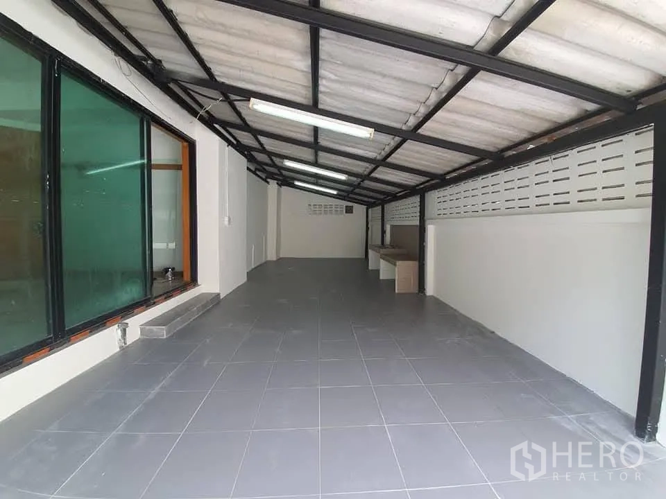 Home Office for rent in Wang Thonglang, Bangkok - Covered carport with tiled floor and metal roof beside large tinted windows.