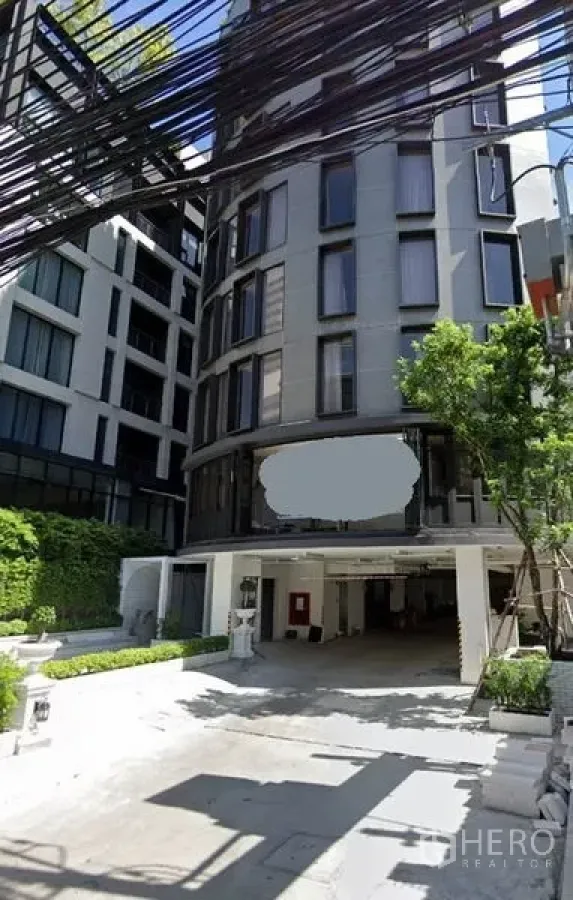 Retail Space for rent in Watthana, Bangkok - Modern mid-rise building exterior with curved glass facade, covered driveway, on-site parking, and landscaped entrance in Watthana, Bangkok.
