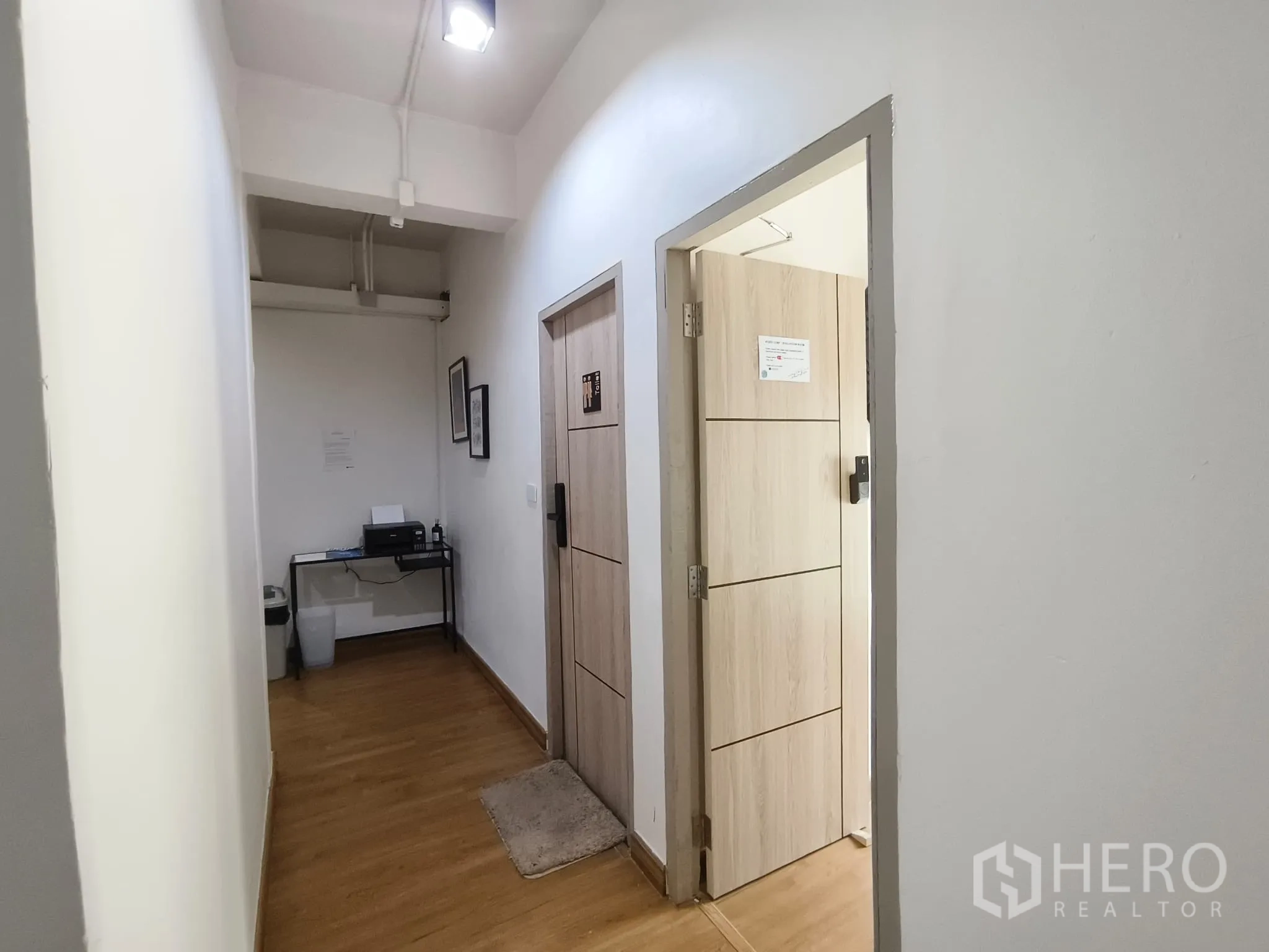 Shophouse for rent in Watthana, Bangkok - Corridor with light wood flooring and doorways to separate rooms.