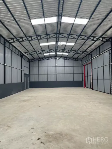 Warehouse for rent in Bang Kapi, Bangkok - Spacious warehouse interior with high steel truss roof, skylights, and smooth concrete floor.
