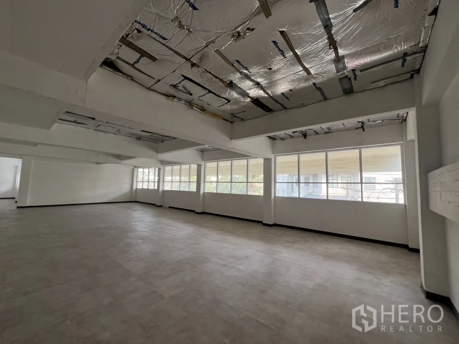 Office Space for rent in Watthana, Bangkok - Bright office space with wall‑to‑wall windows and exposed insulated ceiling panels.