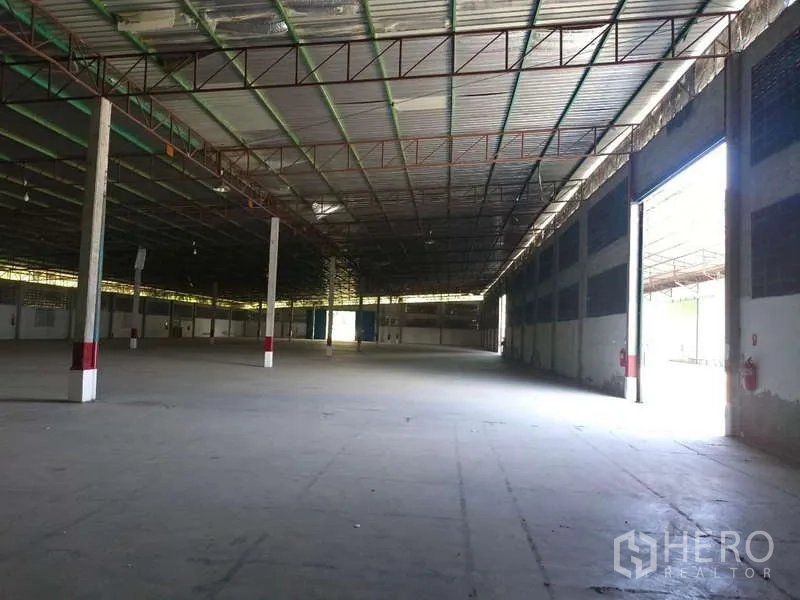 Warehouse for rent in Mueang Rayong, Rayong - Spacious warehouse interior with an open side entrance and concrete floor.