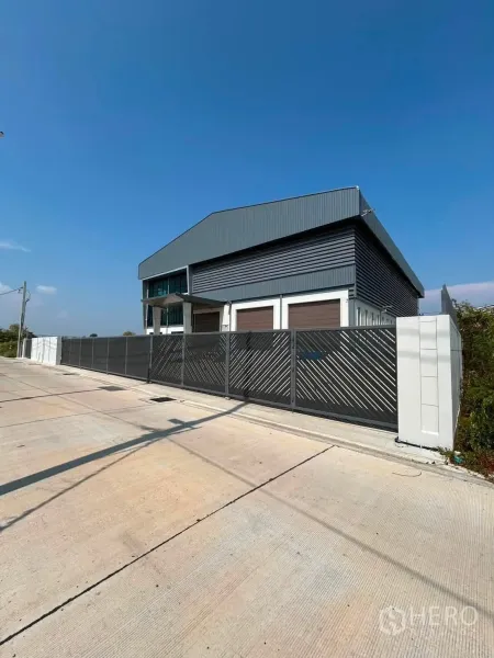 Warehouse for rent in Bang Phli, Samut Prakan - Street-side view of a fenced property with a wide sliding gate and concrete yard.