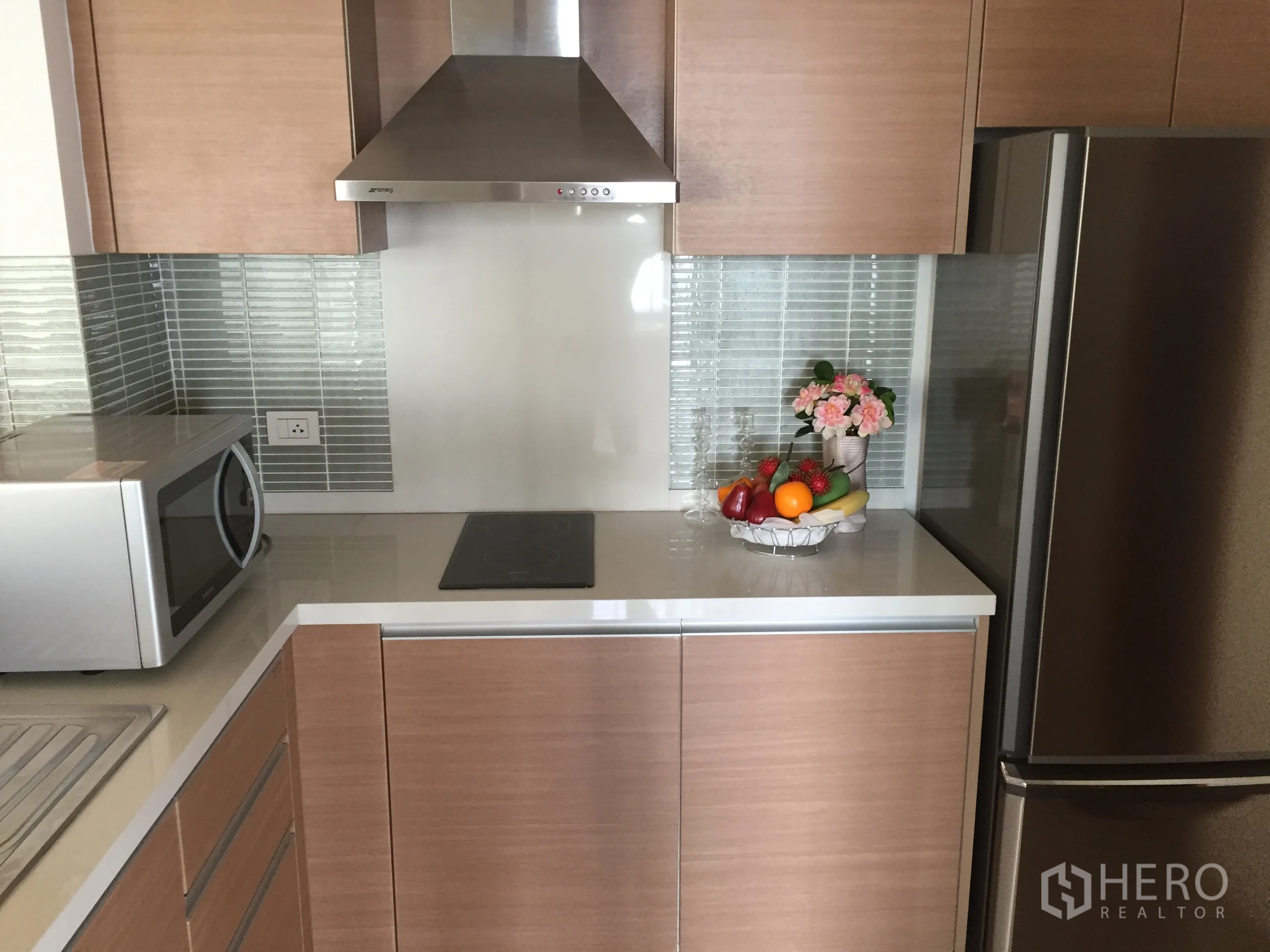 Condominium for rent or sale in Khlong Toei, Bangkok - Modern kitchen with wood cabinets, stainless hood, glass tile backsplash and fridge.