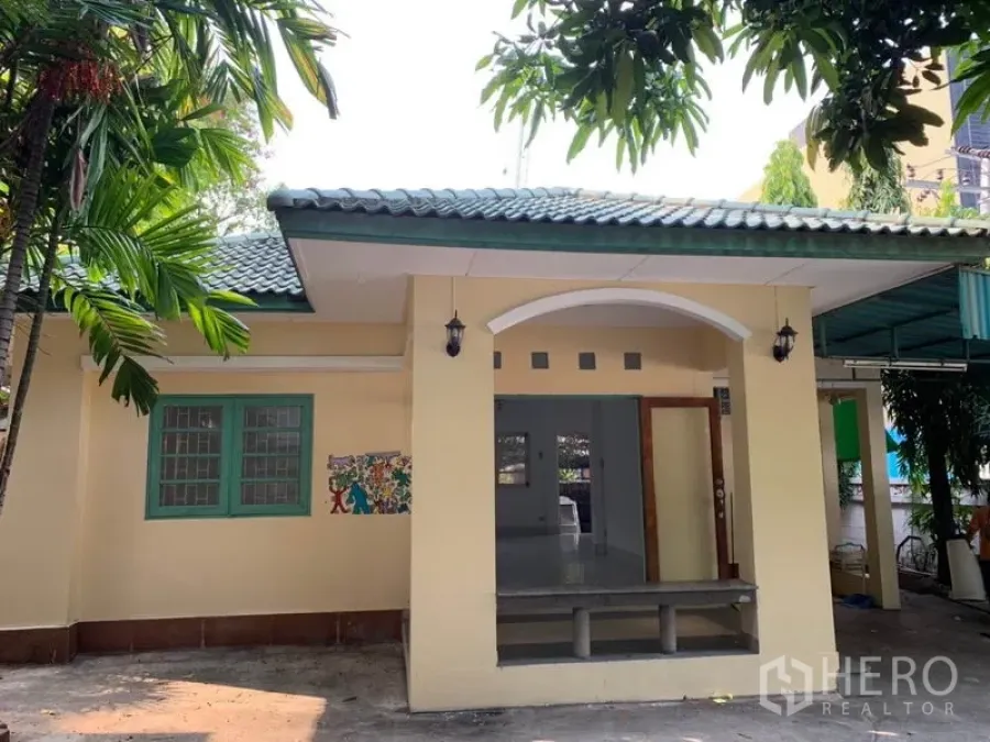 Detached House for rent in Khlong Toei, Bangkok - Single-storey detached house with green tiled roof, covered porch and tropical trees.