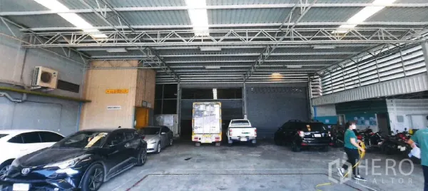 Factory for rent in Yan Nawa, Bangkok - Covered loading bay with high metal roof and multiple vehicles inside the warehouse.