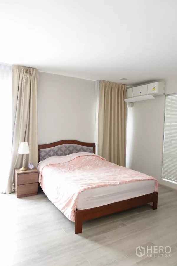 Detached House for rent in Prawet, Bangkok - Air-conditioned master bedroom with double bed, bedside table and full-length curtains.