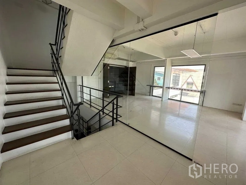 Warehouse for rent in Phra Khanong, Bangkok - Glass-partitioned office beside the staircase with city-view windows.