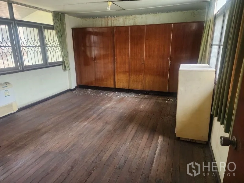 Detached House for rent in Watthana, Bangkok - Bedroom with long built-in wooden wardrobes, hardwood floor and multiple windows.