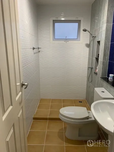 Detached House for sale in Prawet, Bangkok - Compact bathroom with window, shower zone and white sanitaryware.