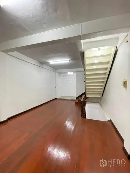 Shophouse for sale in Phra Khanong, Bangkok - Bang Chak shophouse interior with polished wood floor, white walls and a side staircase to upper levels.