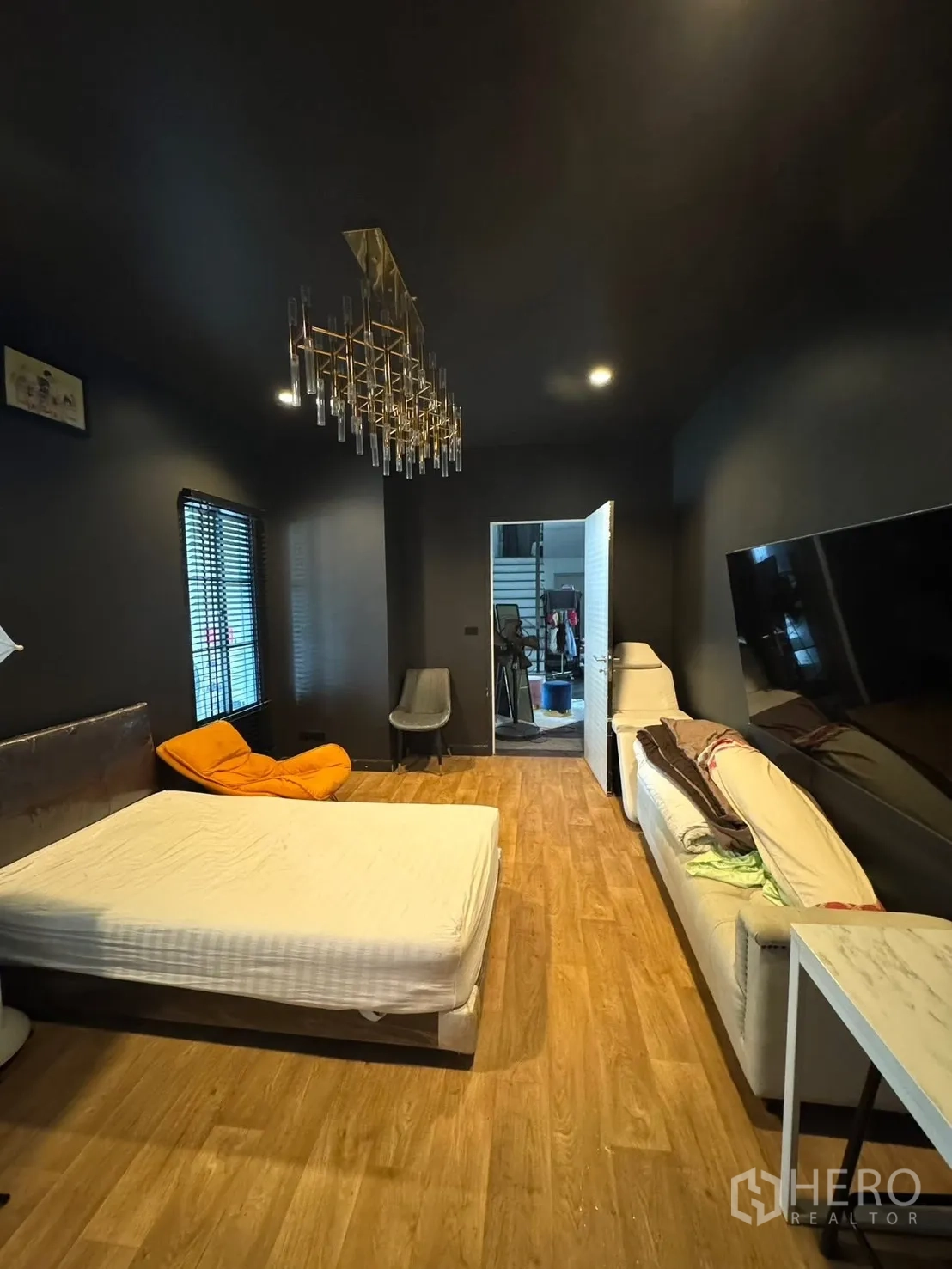 Detached House for sale in Mueang Pathum Thani, Pathum Thani - Dark‑themed bedroom with chandelier, sofa and TV wall.