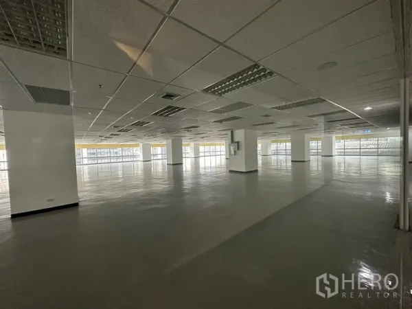 Office Space for rent - Large empty office space with grid ceiling lighting and wraparound glazing for abundant daylight.
