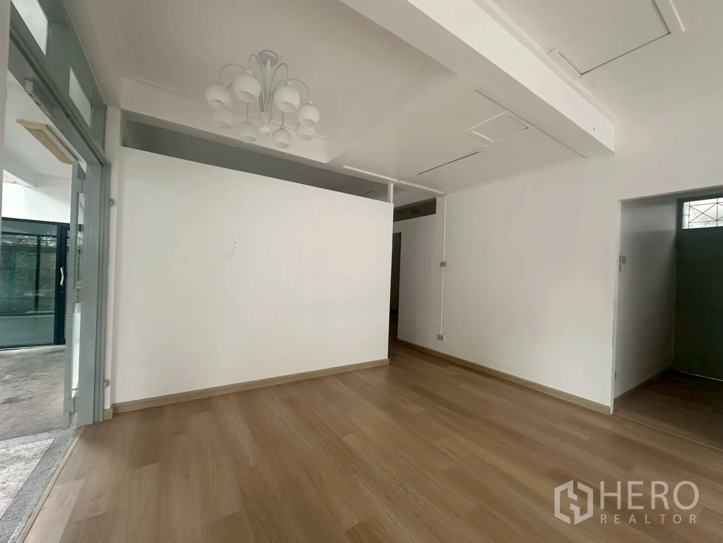 Detached House for rent in Watthana, Bangkok - Compact room with chandelier, wood floors, and sliding glass access to the terrace.
