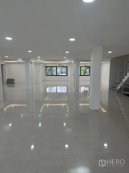 Office Space for rent or sale in Huai Khwang, Bangkok - Open workspace with wide windows and a staircase access to upper floors.