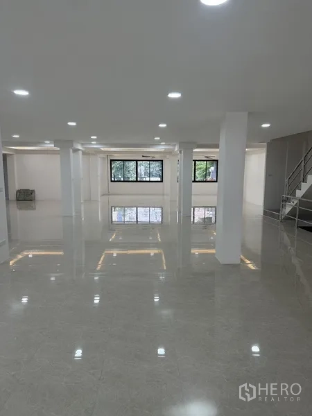 Office Space for rent or sale in Huai Khwang, Bangkok - Open workspace with wide windows and a staircase access to upper floors.