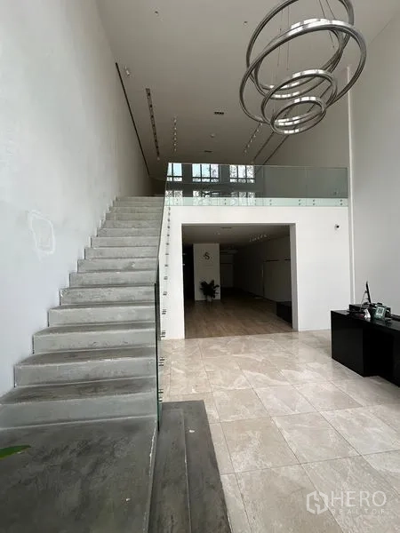Home Office for rent in Phra Khanong, Bangkok - Entry hall with concrete staircase, mezzanine level and pendant lighting.