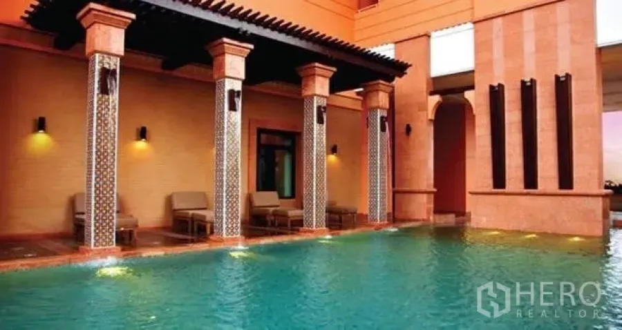 Condominium for rent in Khlong Toei, Bangkok - Resort-style swimming pool with shaded lounge, decorative columns and warm terracotta walls.