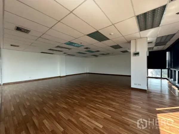 Office Space for rent in Watthana, Bangkok - Spacious unfurnished office area with wood flooring and grid ceiling lighting.