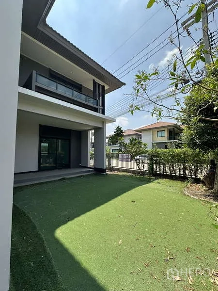 Detached House for sale in Lam Luk Ka, Pathum Thani - Side garden with artificial grass and a shaded terrace area.