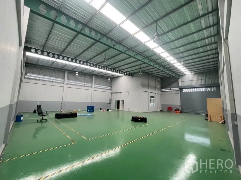 Factory for rent in Lam Luk Ka, Pathum Thani - High-ceiling warehouse with green epoxy floor, skylights, and loading doors.